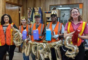 CoWorx workers in safety vests holding congrats balloons